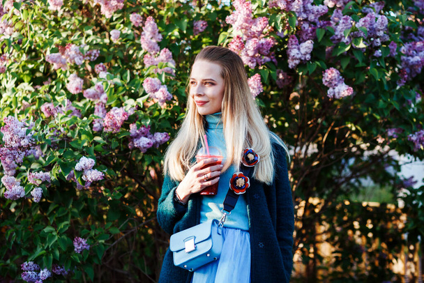 Pretty caucasian woman is spending time outdoors in spring, drinking fruit juice, cocktail.  - Valokuva, kuva