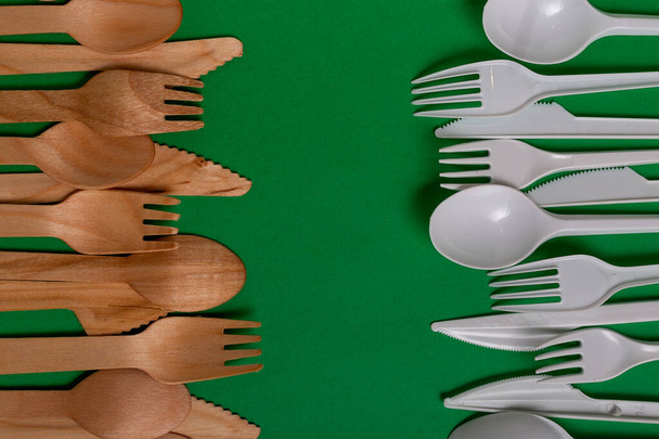 From above plastic utensils versus ecological lumber forks and knives against freen background. - Photo, Image