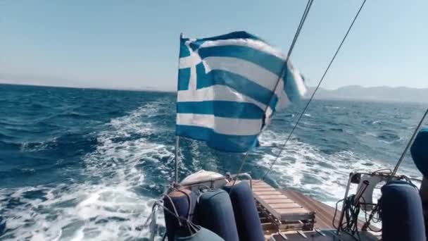 Плавуча подорож з човном посеред океанічної протоки Греції влітку. Гаряча вітряна погода зробила грецький прапор розмахуючи на човні. - Кадри, відео