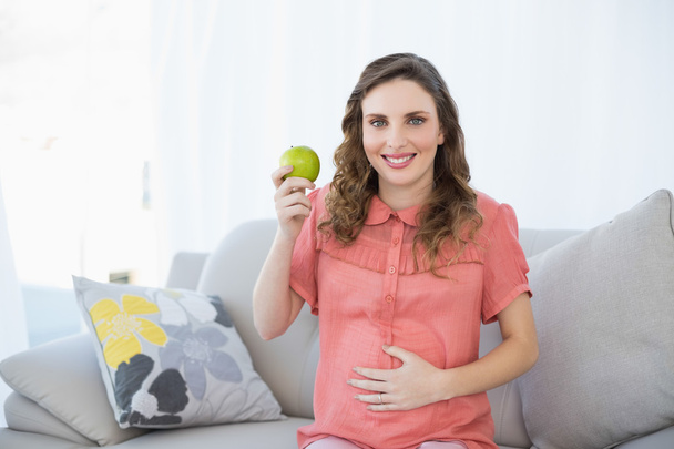 Young pregnant woman showing green apple - 写真・画像