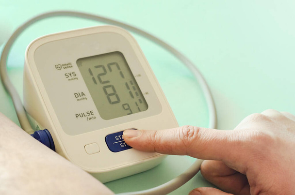 Digitální tonometr. Monitor krevního tlaku. Elektronický monitor krevního tlaku a ruce na modrém pozadí. Zdravotní koncepce. Kardiologie - Péče o srdce - Fotografie, Obrázek