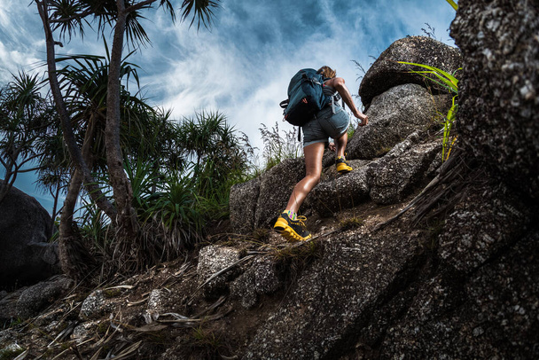 Woman hiker with backpack climbs steep rocky terrain - Fotó, kép