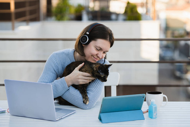 Female remote working remotely at home terrace with her pet - Foto, afbeelding