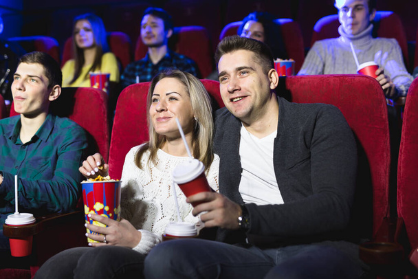 Щаслива молода пара сидить у кіно і насолоджується переглядом фільму
. - Фото, зображення