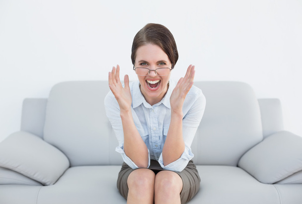 Displeased well dressed woman screaming on sofa - Foto, imagen