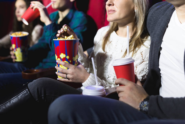 Ευτυχισμένο νεαρό ζευγάρι που κάθεται στον κινηματογράφο και απολαμβάνει να βλέπει την ταινία. - Φωτογραφία, εικόνα