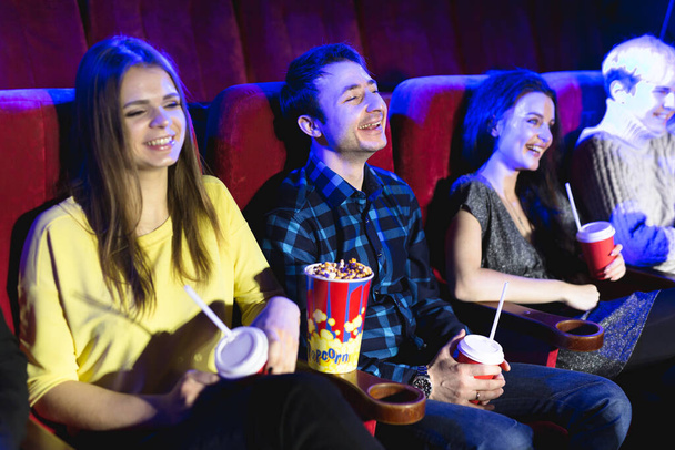 Gli amici si siedono e mangiano popcorn insieme mentre guardano film in un cinema
. - Foto, immagini