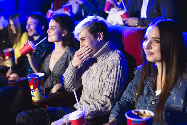 Друзья сидят и едят попкорн вместе во время просмотра фильмов в кинотеатре
. - Фото, изображение