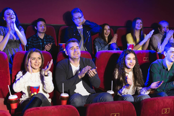 Ευτυχισμένο χαμογελαστό κοινό χειροκροτεί ενώ κάθεται στον κινηματογράφο και βλέποντας ταινία. - Φωτογραφία, εικόνα