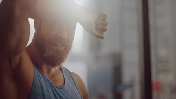 Portrait of Strong Bearded Male Athlete Wearing Sleeveless Shirt Wipes Sweat From His Forehead with His Muscular Hand. Handsome Man after Hardcore Exercise and Training. Man Gets Job Done - Кадри, відео