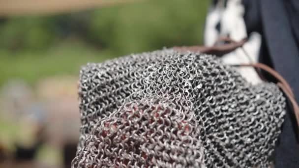 Medieval knight wearing traditional steel chain armor and holding sword with cross sign. Close up of a warrior in chainmail armor, medieval vendor selling warlike costume on marketplace - Filmagem, Vídeo