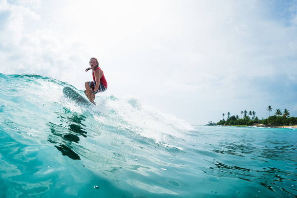 Surfer jedzie na fali oceanu z palmami na tle - Zdjęcie, obraz
