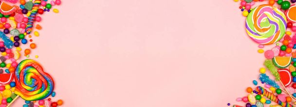カラフルな甘いキャンディー。オーバーヘッドビューピンクのバナーの背景を持つ両面境界線. - 写真・画像