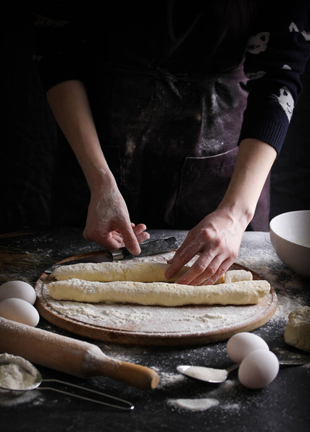 Concept of Russian cuisine. Lazy dumplings on a dark background with hands. Cooking process - 写真・画像