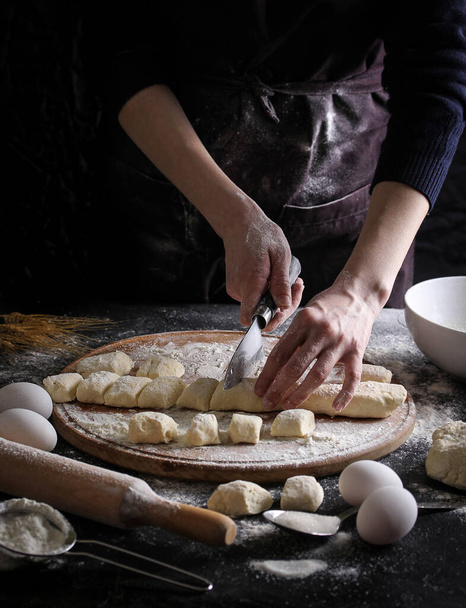 Έννοια της ρωσικής κουζίνας. Τεμπέλικα ζυμαρικά σε σκούρο φόντο με τα χέρια. Διαδικασία μαγειρέματος - Φωτογραφία, εικόνα