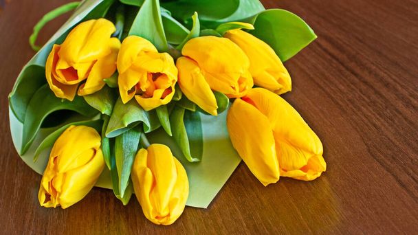 Tulipes jaune vif sur une table en bois close-up. Vue latérale. Bonne humeur
. - Photo, image