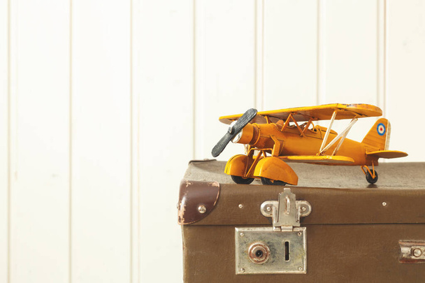 Toy yellow metal plane Old retro suitcases White wooden background Vintage tinting Copy space - Foto, Imagem