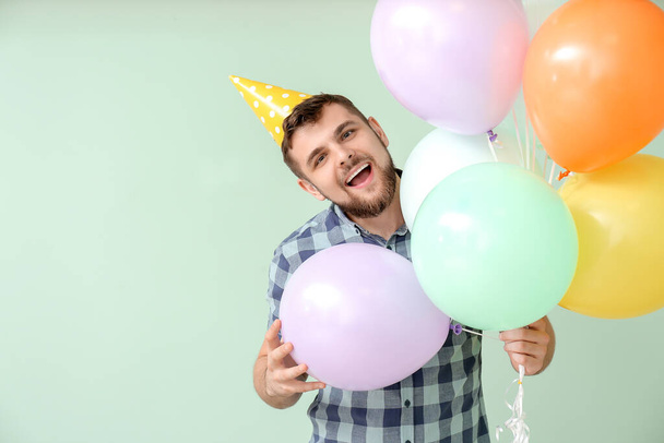 Komea mies juhlii syntymäpäivää väritaustalla - Valokuva, kuva