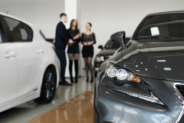 Auto επιχείρηση, πωλήσεις αυτοκινήτων - ένα ζευγάρι των φίλων των κοριτσιών με έναν αντιπρόσωπο αυτοκινήτων επιλέξτε ένα αυτοκίνητο σε μια αντιπροσωπεία αυτοκινήτων - Φωτογραφία, εικόνα
