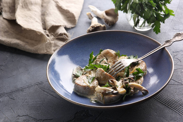 Bull eggs with mushrooms and parsley in a cream sauce in a blue bowl on a dark grey background. Background image, copy space - Fotografie, Obrázek