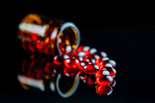 Red medical capsules close-up on a black background - Fotoğraf, Görsel