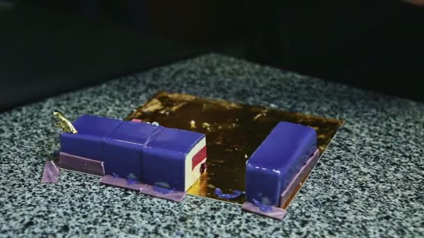 ženské ruce nožem odnést kousky fialové glazované pěny dort s ovocným želé - Záběry, video