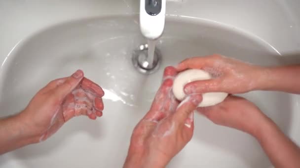 浴室やトイレでぬるま湯で消毒石鹸で手を洗う2人のトップビュー。人々の間でウイルスや微生物の拡大を防ぐための厳格な指示を持つ毎日の衛生 - 映像、動画