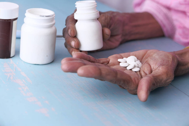 Літня жінка виливає таблетки з пляшки на руку, вид зверху
 - Фото, зображення