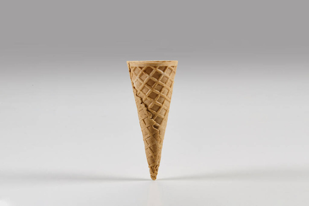 Cone de bolacha pequeno vazio e doce para sorvete isolado no fundo branco. Conceito de comida e guloseimas. Mockup, modelo para sua publicidade e design. Fechar, espaço de cópia
 - Foto, Imagem