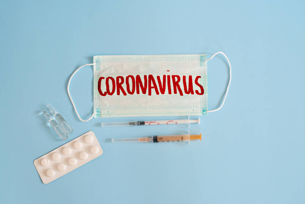 Koronavirüs - 2019 nkov virüsü konsepti, WUHAN. Tıbbi şırıngalar ve ampullerle CORONAVIRUS yazılı cerrahi maske koruyucu. Çin Coronavirüs salgını. Salgın. - Fotoğraf, Görsel