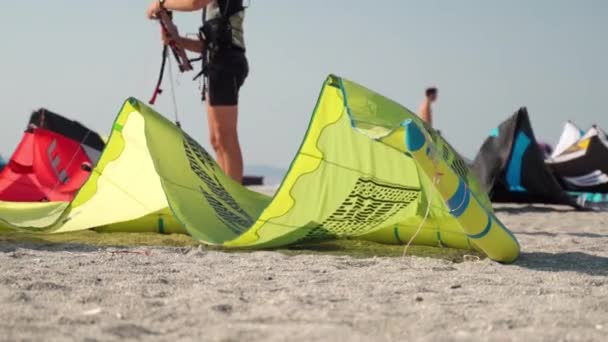 Extreme watersport op het strand, professionele surfers bereiden apparatuur voor de lancering, kleurrijke vliegers liggen op het zand en wind waait. Kite surfen adrenaline - Video