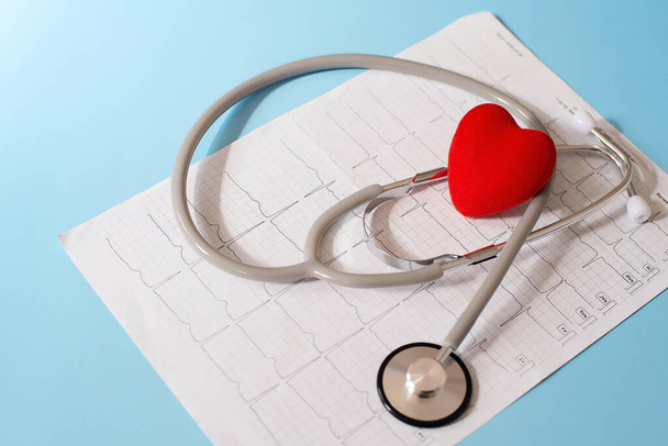 Medical stethoscope and red heart lying on a cardiogram. Cardiotherapist, heart rate monitor, cardiac physics, heart rate measurement, arrhythmia, 911, as well as the concept of resuscitation. - Photo, Image