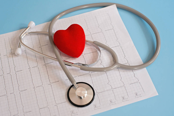 Medical stethoscope and red heart lying on a cardiogram. Cardiotherapist, heart rate monitor, cardiac physics, heart rate measurement, arrhythmia, 911, as well as the concept of resuscitation. - Photo, Image