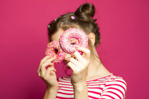 Пончик в женских руках на ярком розовом фоне, концепция диеты
 - Фото, изображение