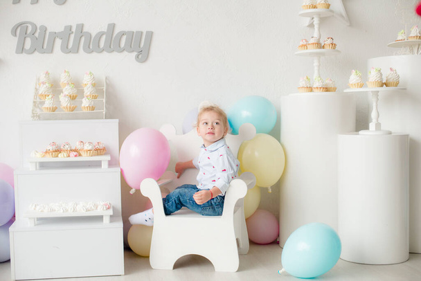 Cute little boy with blond hair on his birthday at a children's party with balloons and cakes. Children's party. Balloons - Photo, Image