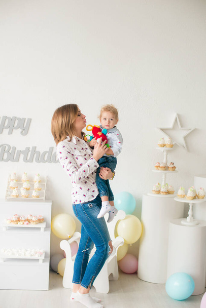 Young mother with her little cute son on his birthday at a children's party with balloons and cakes. Children's party. Balloons. Happy childhood - 写真・画像