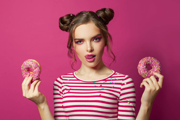 Colorful portrait of nice model woman holding donut on vivid pink background - Zdjęcie, obraz