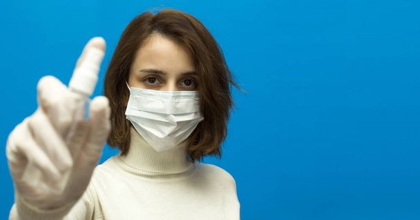 Een vrouw met een beschermend masker en handschoenen heeft een ontsmettingsmiddel tegen het coronavirus. Witte kleren en handschoenen. ontsmettingsmiddel. Banner - Foto, afbeelding