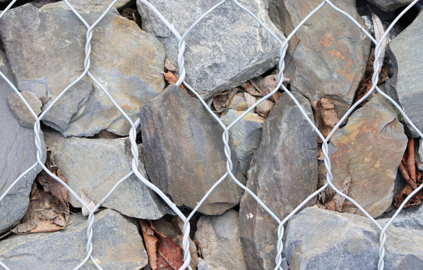 stone fence in a steel mesh. background of stones - Photo, Image