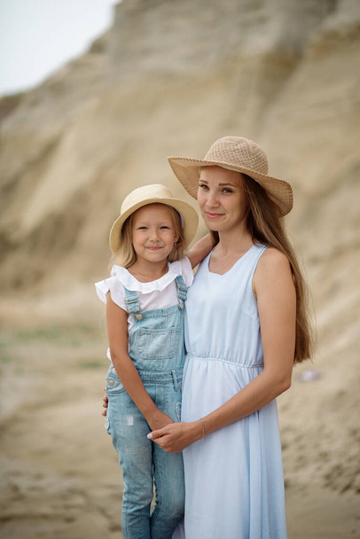 8 years old girl whith her mom in jeans clothes on a sandy beach - Fotoğraf, Görsel