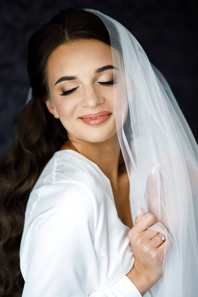 Bride with wedding makeup and hairstyle. Attractive bride in white robe in wedding morning. - Foto, Bild