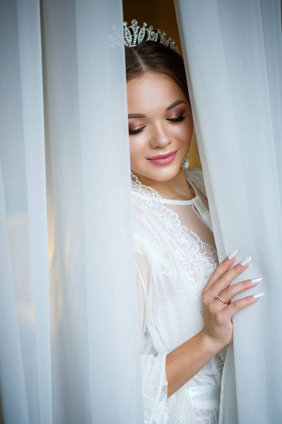 mooie bruid in een bruiloft ochtend in een badjas en sluier - Foto, afbeelding