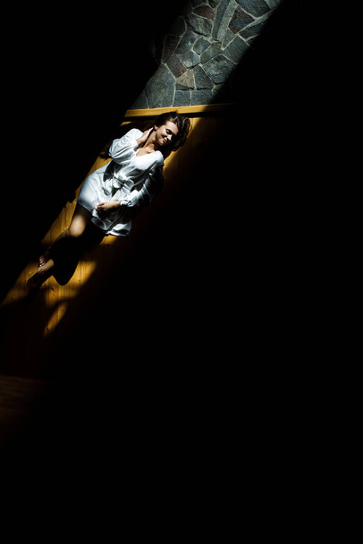 Beautiful girl lies on the wooden floor. Light falls through the window onto the floor. - Fotó, kép