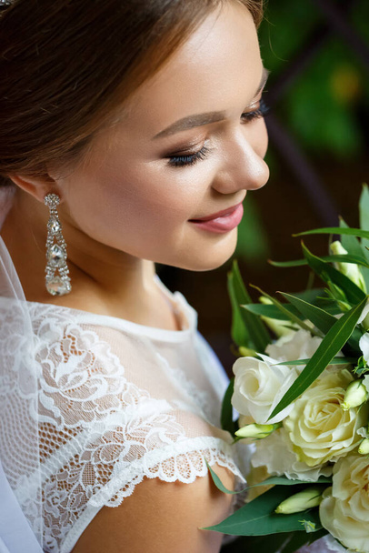 belle mariée en voile et manteau blanc assis sur une couverture avec un bouquet de mariage dans ses mains
 - Photo, image
