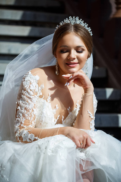 白いウェディングドレスを着た美しい花嫁が階段に座り、美しく笑顔 - 写真・画像