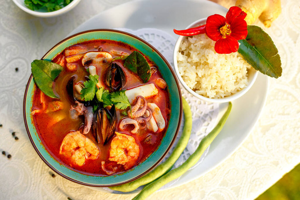 Zuppa tailandese Tom yam con frutti di mare (polpo, gamberetti), erbe e verdure servite in tavola con ingredienti, cibo sano
 - Foto, immagini
