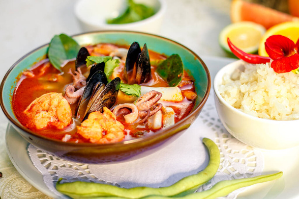inhame tom sopa tailandesa com frutos do mar (polvo, camarões), ervas e legumes servidos na mesa com ingredientes, alimentos saudáveis
 - Foto, Imagem