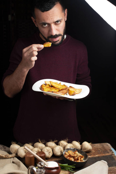 Mann isst hausgemachte Pommes mit dunklem Hintergrund - Foto, Bild