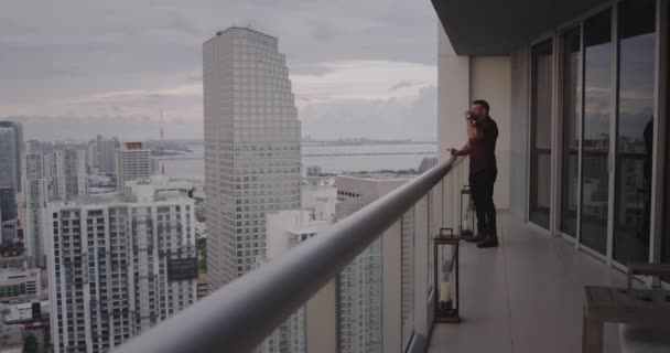 Hombre fumando cigarro en balcón al atardecer
 - Imágenes, Vídeo