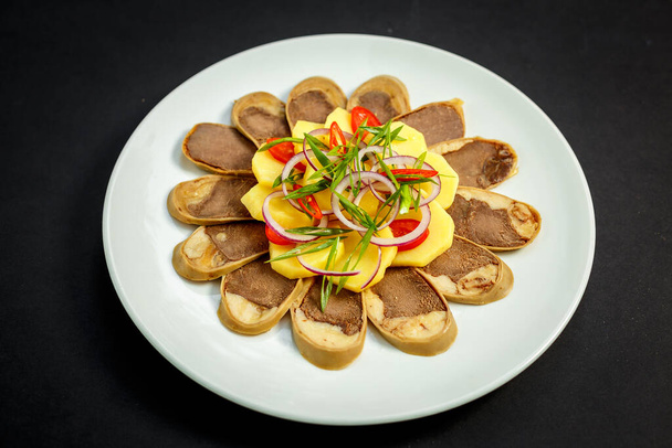 Kazachse keuken, vlees met gekookte aardappelen uien en kruiden, op een wit bord - Foto, afbeelding